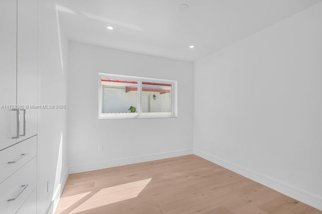 empty room featuring light wood-type flooring, baseboards, and recessed lighting