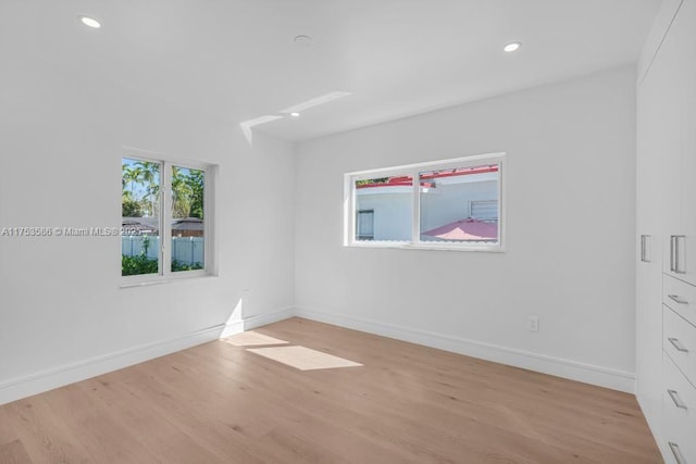 spare room featuring light wood finished floors, recessed lighting, and baseboards