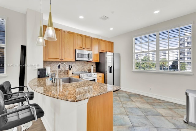 kitchen featuring stainless steel appliances, a sink, visible vents, backsplash, and light stone countertops