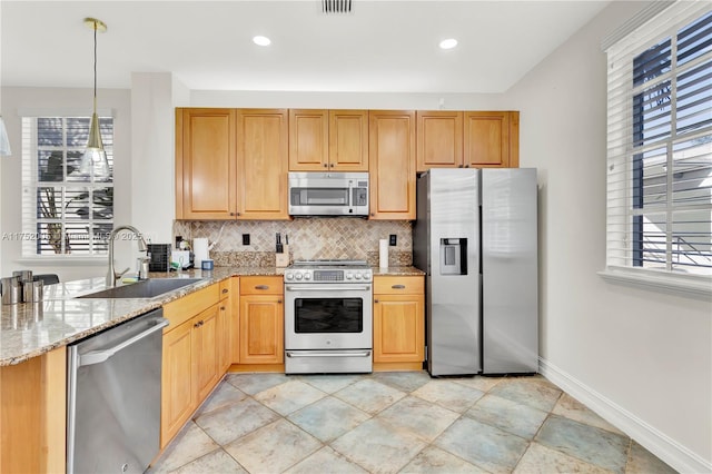 kitchen featuring stainless steel appliances, a sink, baseboards, light stone countertops, and tasteful backsplash