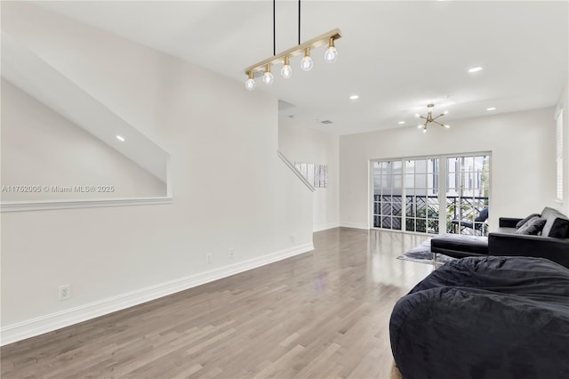 living area with recessed lighting, a notable chandelier, baseboards, and wood finished floors