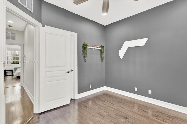 empty room featuring ceiling fan, wood finished floors, visible vents, and baseboards