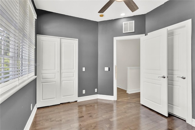 unfurnished bedroom featuring a closet, wood finished floors, visible vents, and baseboards