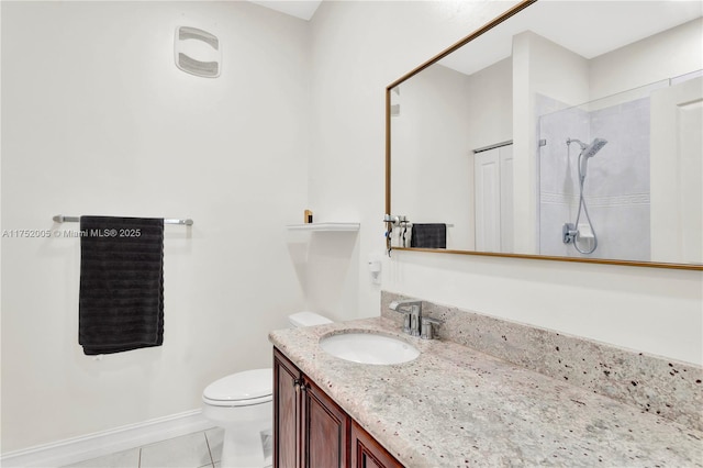 bathroom featuring tile patterned flooring, toilet, vanity, baseboards, and tiled shower