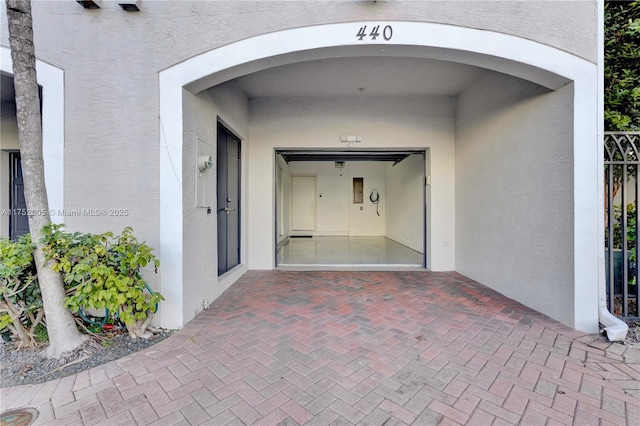 view of exterior entry featuring decorative driveway and stucco siding