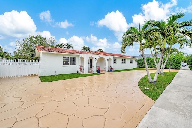 mediterranean / spanish home featuring driveway, fence, a tiled roof, and stucco siding