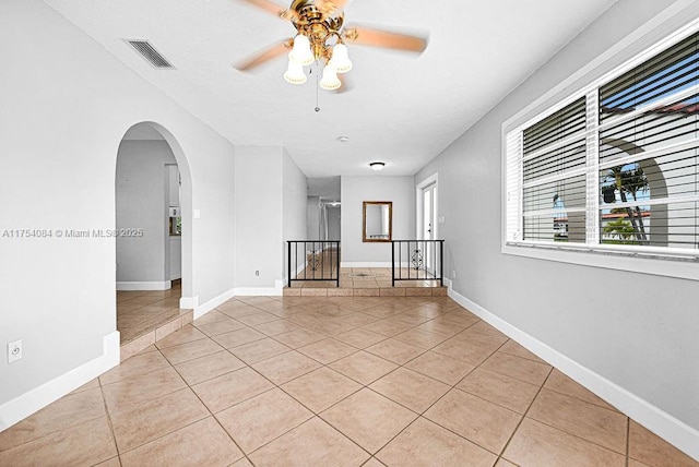 spare room with arched walkways, visible vents, baseboards, and light tile patterned floors