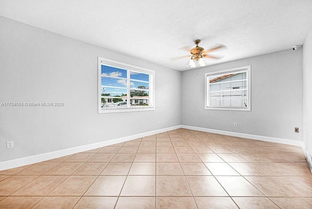 empty room featuring ceiling fan, baseboards, and light tile patterned floors