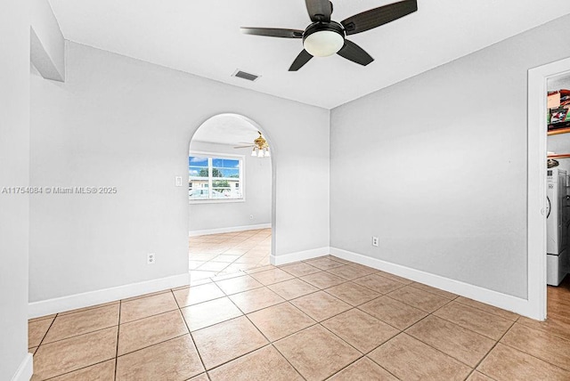 empty room with arched walkways, visible vents, baseboards, and light tile patterned floors