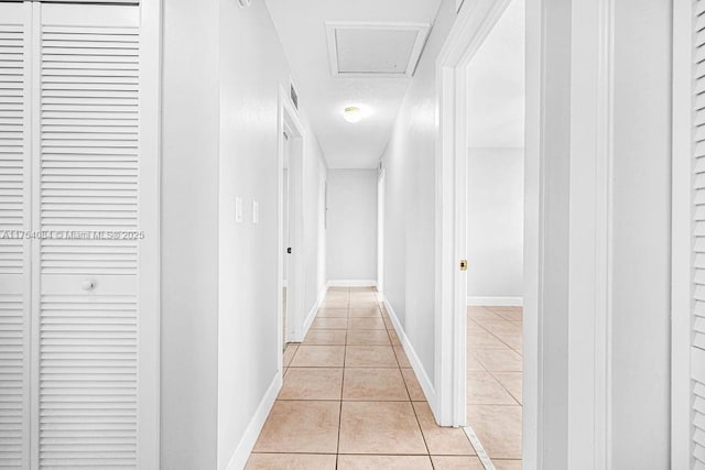 hallway with light tile patterned floors and baseboards