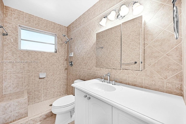 bathroom with tile walls, toilet, a tile shower, vanity, and tile patterned flooring