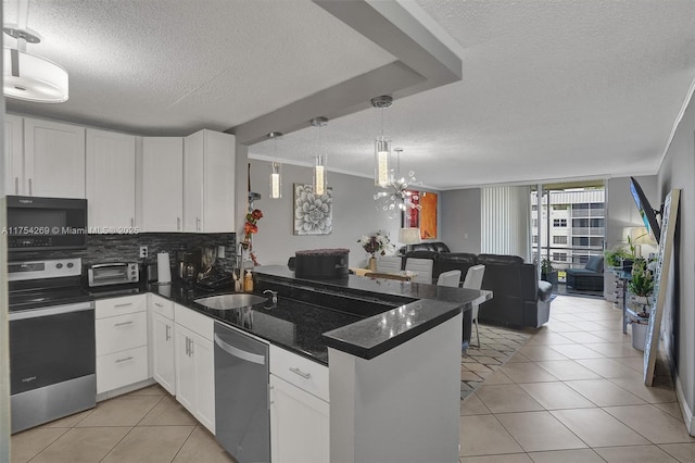 kitchen with light tile patterned floors, backsplash, appliances with stainless steel finishes, open floor plan, and a peninsula