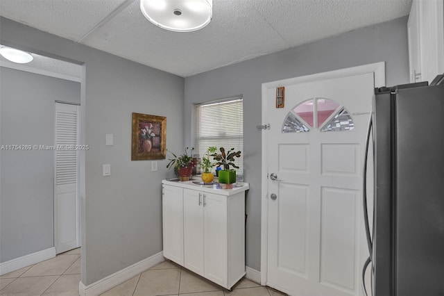 entrance foyer featuring light tile patterned floors, a textured ceiling, and baseboards