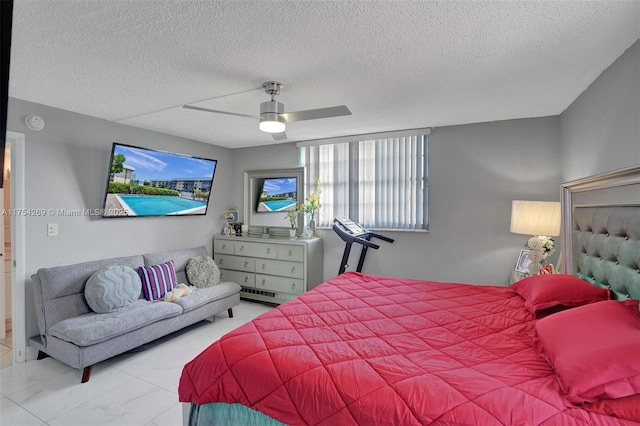 bedroom with marble finish floor, a textured ceiling, and a ceiling fan