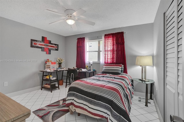 bedroom featuring ceiling fan, baseboards, a textured ceiling, and light tile patterned flooring