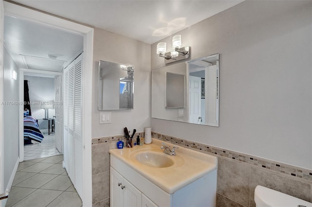 bathroom with tile walls, toilet, tile patterned floors, vanity, and a notable chandelier