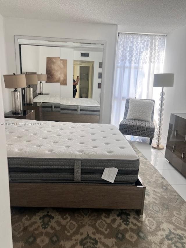 tiled bedroom with a textured ceiling and visible vents