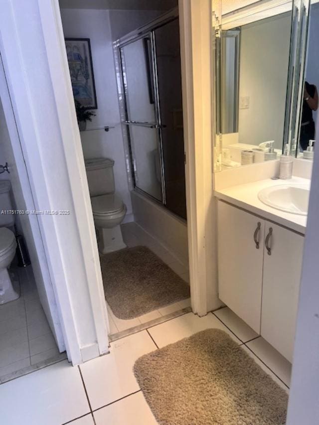 full bathroom with tile patterned flooring, shower / bath combination with glass door, vanity, and toilet