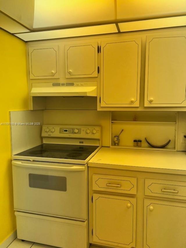 kitchen with light tile patterned flooring, under cabinet range hood, baseboards, light countertops, and white electric range oven