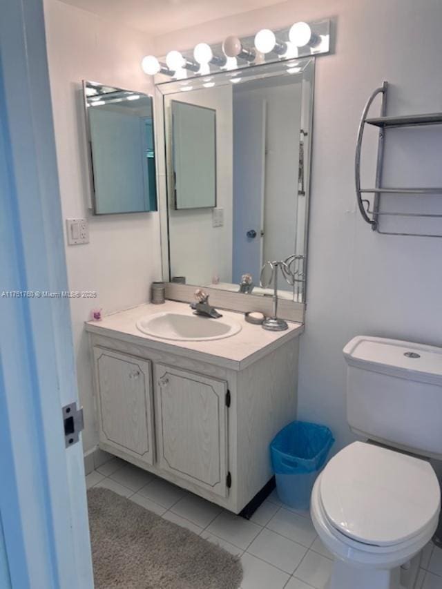 half bath featuring vanity, tile patterned flooring, and toilet