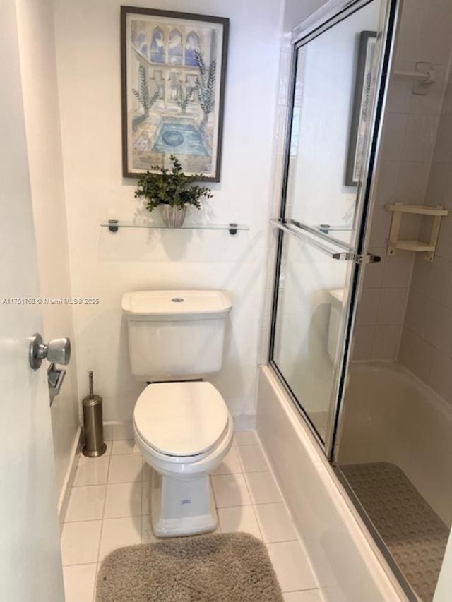 full bath featuring toilet, shower / bath combination with glass door, tile patterned flooring, and baseboards