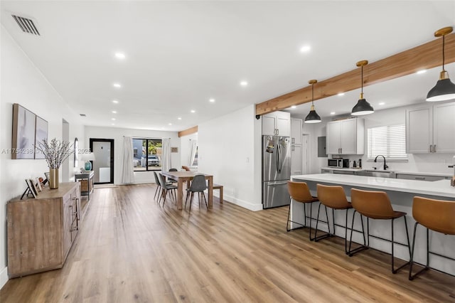 kitchen with visible vents, a breakfast bar, freestanding refrigerator, light wood-type flooring, and a sink