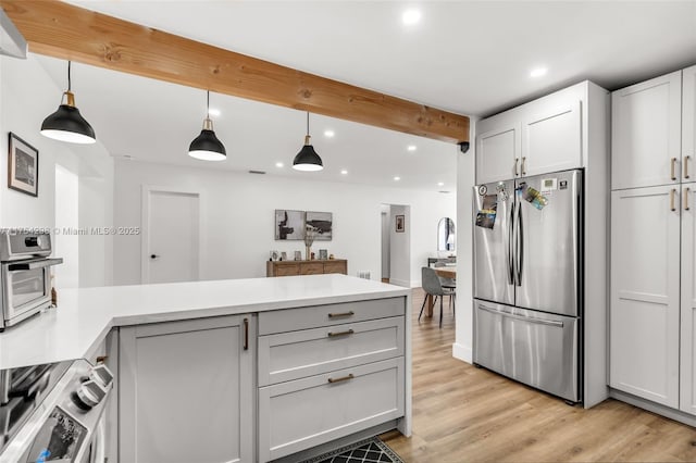 kitchen featuring beam ceiling, light countertops, freestanding refrigerator, light wood-type flooring, and a peninsula