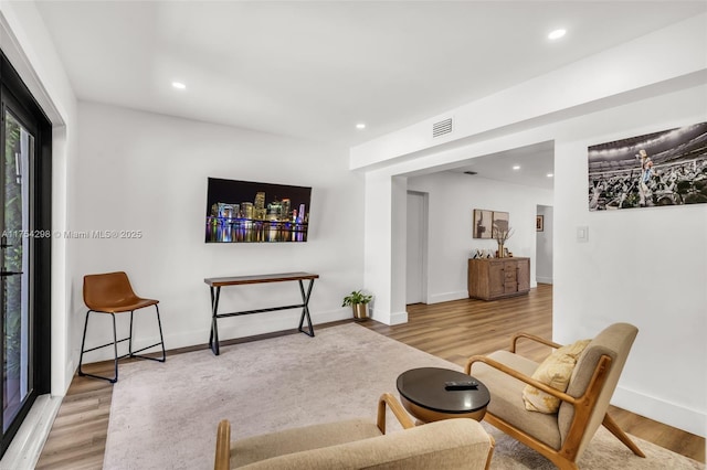 living area with baseboards, wood finished floors, visible vents, and recessed lighting