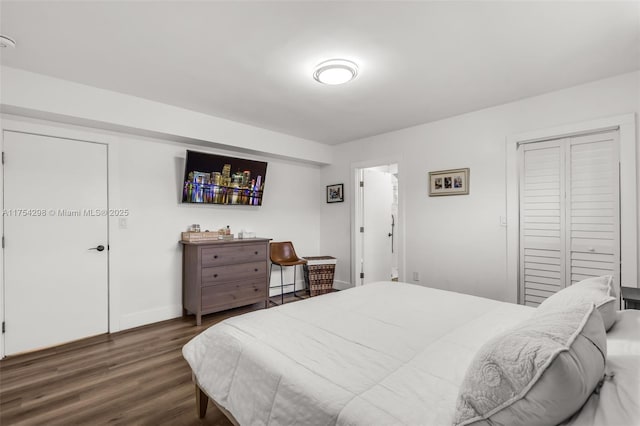 bedroom featuring a baseboard heating unit, a closet, baseboards, and wood finished floors