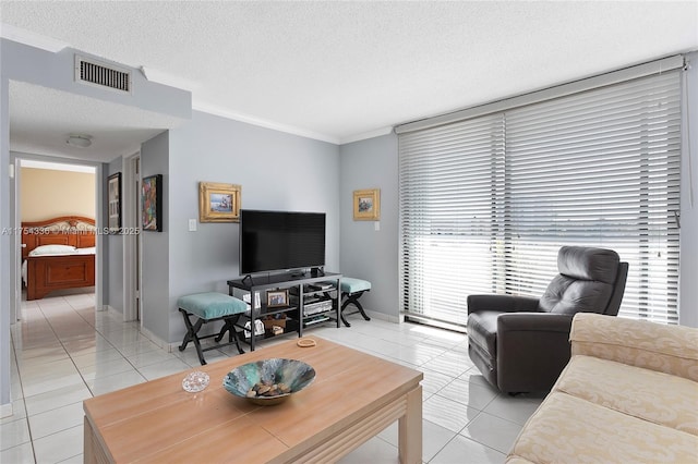 living room with light tile patterned floors, a textured ceiling, visible vents, baseboards, and crown molding