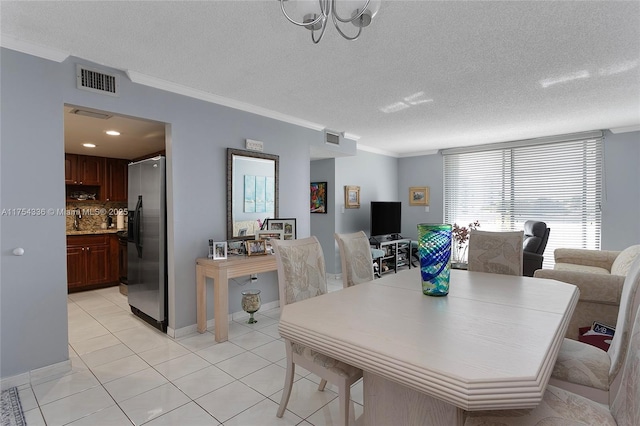 dining area with a textured ceiling, light tile patterned flooring, visible vents, and crown molding