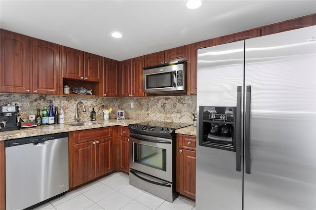 kitchen featuring stainless steel appliances, tasteful backsplash, a sink, and light stone counters