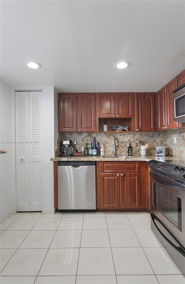 kitchen with stainless steel appliances, tasteful backsplash, a sink, and light stone countertops