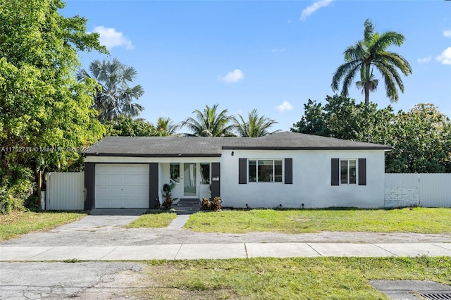 single story home featuring an attached garage, fence, driveway, stucco siding, and a front lawn