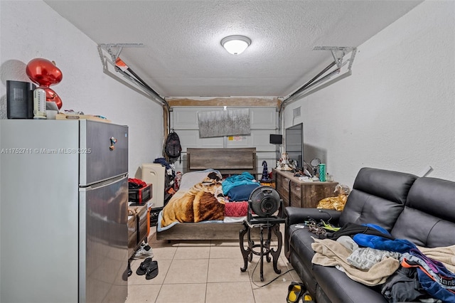 interior space featuring tile patterned flooring, a textured ceiling, and freestanding refrigerator