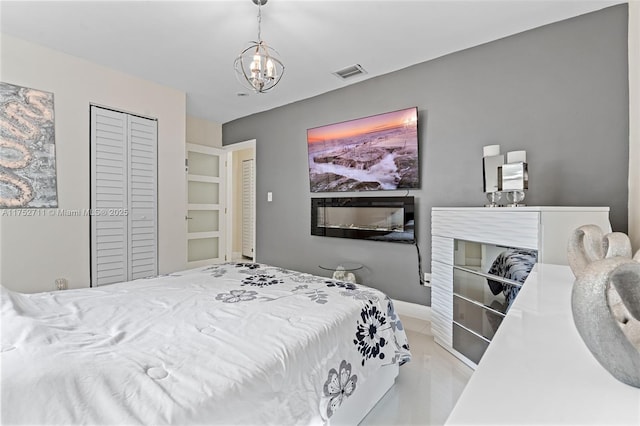 bedroom featuring a closet, visible vents, an inviting chandelier, a glass covered fireplace, and baseboards