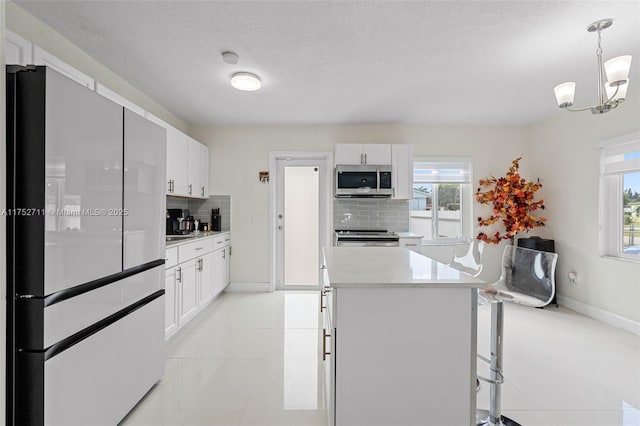 kitchen featuring white cabinets, tasteful backsplash, stainless steel appliances, and light countertops