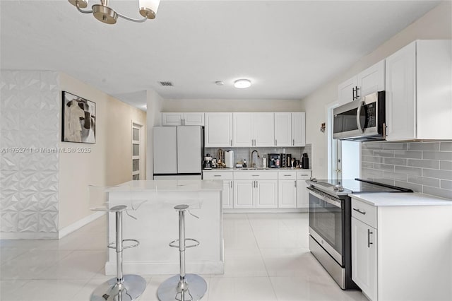 kitchen featuring light tile patterned floors, stainless steel appliances, a sink, white cabinetry, and light countertops