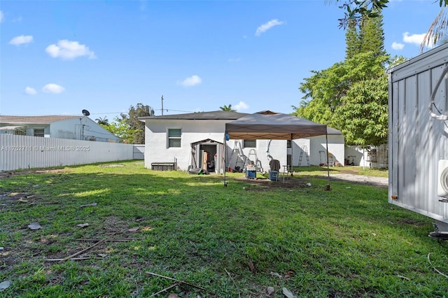 rear view of property with stucco siding, a lawn, an outdoor structure, and fence