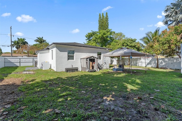 rear view of house featuring a fenced backyard, a yard, and stucco siding