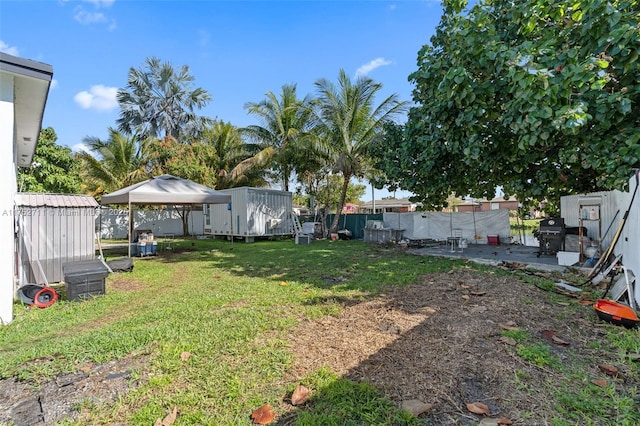 view of yard with an outdoor structure, fence, and a storage unit