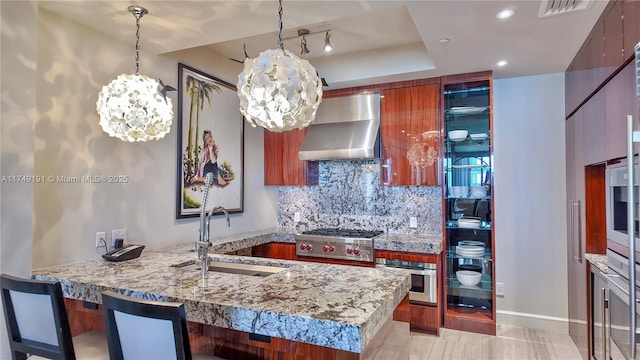 kitchen featuring a tray ceiling, visible vents, appliances with stainless steel finishes, a sink, and wall chimney range hood