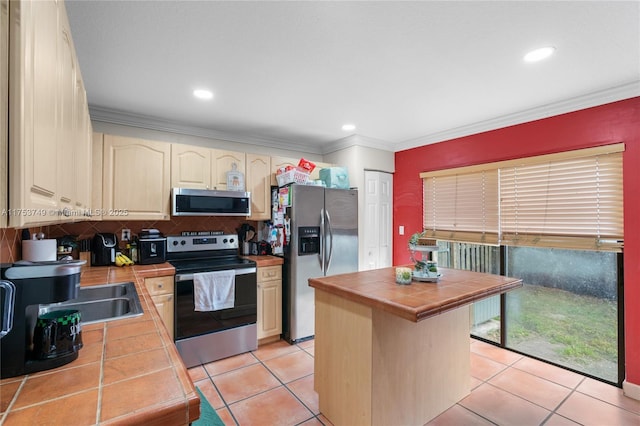 kitchen with tile counters, stainless steel appliances, and crown molding