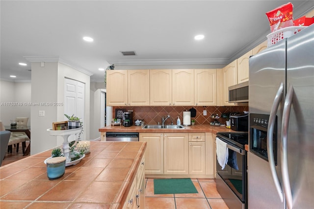 kitchen with tile countertops, stainless steel appliances, a sink, visible vents, and crown molding