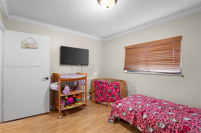 bedroom with a textured ceiling, ornamental molding, and wood finished floors