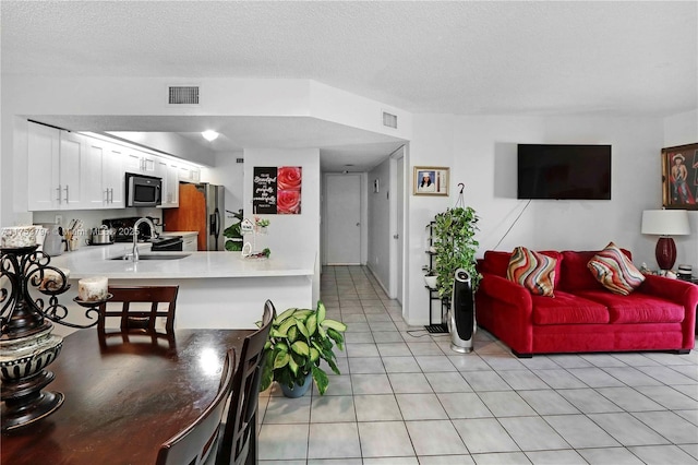 living room featuring light tile patterned floors, a textured ceiling, and visible vents