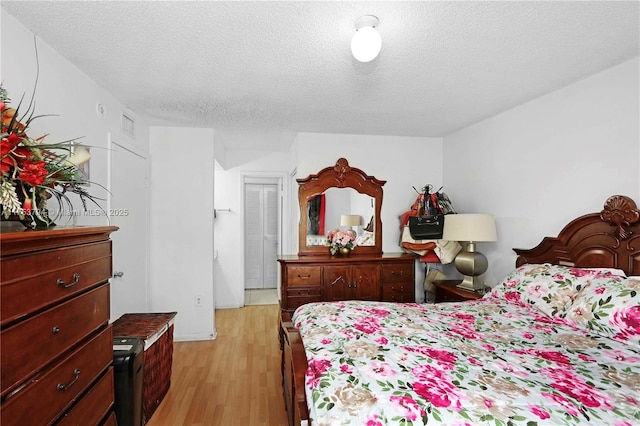 bedroom with light wood finished floors and a textured ceiling