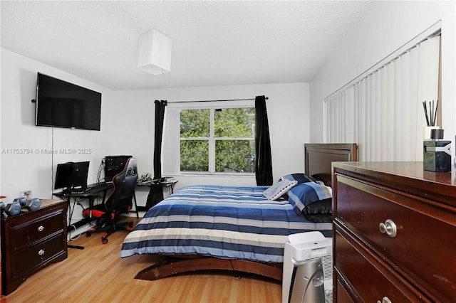 bedroom with light wood-style floors and a textured ceiling