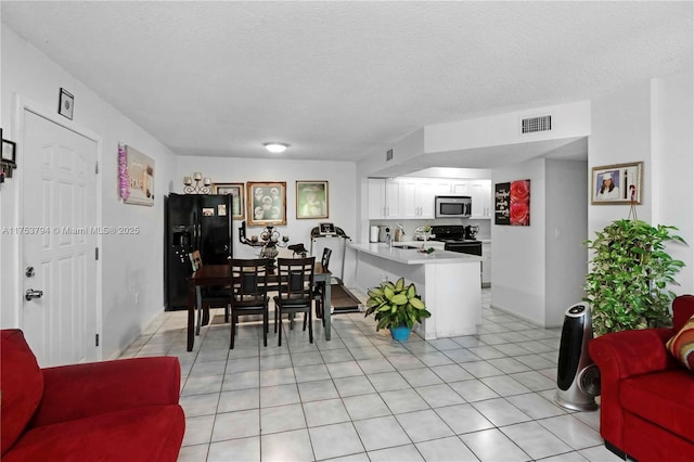 dining space featuring visible vents, a textured ceiling, and light tile patterned floors