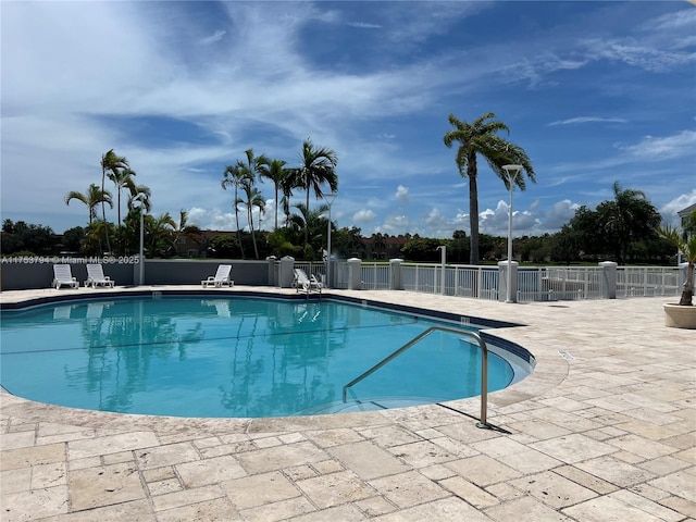 community pool with a patio area and fence